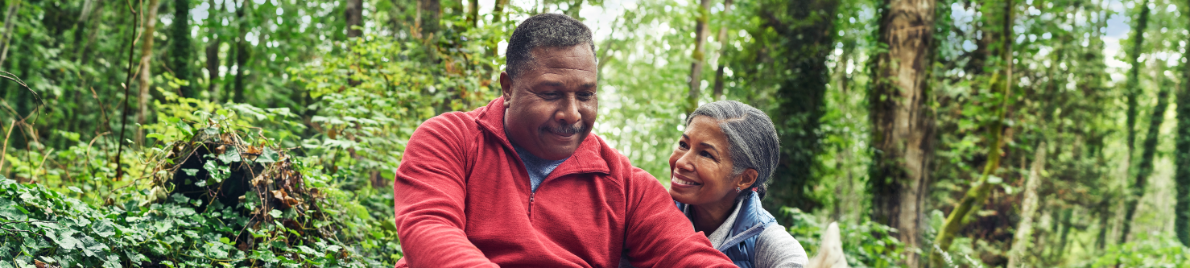 A mature African American couple against a forest backdrop.