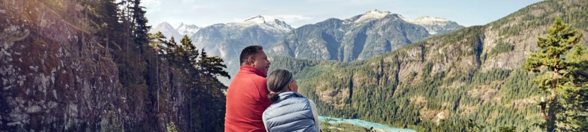 A couple sits on a bluff admiring a view of distant
                    mountains.